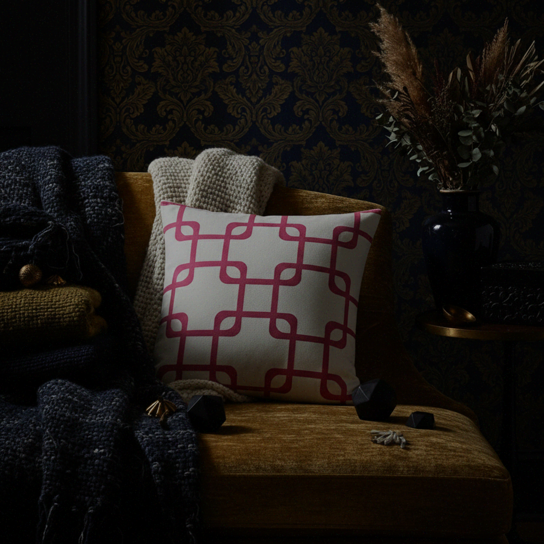 Decorative pillow with red geometric pattern on a brown chair against a dark wall.