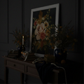 Floral artwork on a dark wall with decorative items on a table.