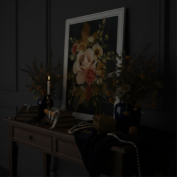 Floral artwork on a dark wall with decorative items on a table.